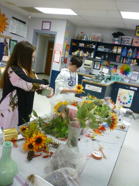 Students work on Thanksgiving centerpieces using dried flowers, pine cones and artificial fall foliage.