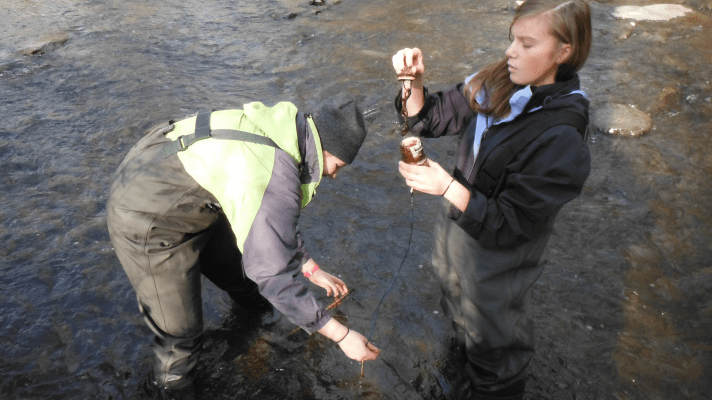 Lyndsay and Jordan check the ibutton sensor and collect water samples at Mill Brook.