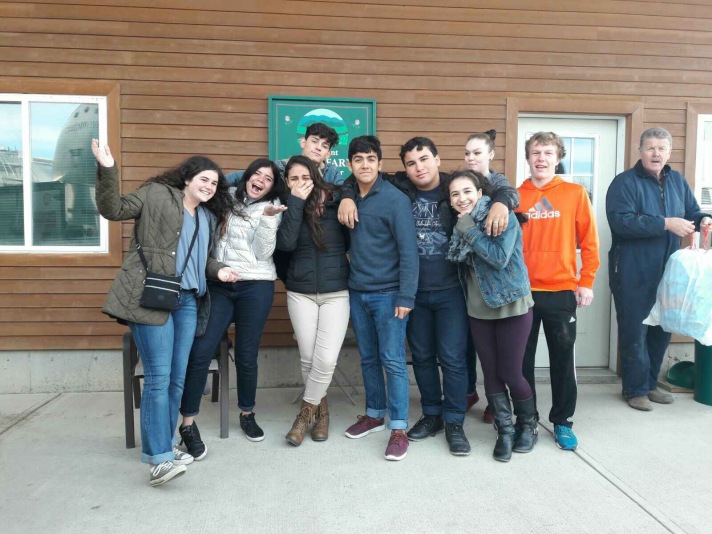 (Puerto Rican students and BFA students pose outside the milking barn at Bill Rowell’s (far right) “Cow Power” farm in Sheldon, VT.  Photo credit, Teresa Larose.)