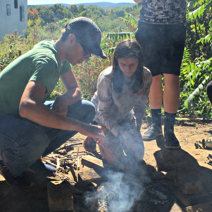 Alex H and Rachel P work to build a fire to cook their lunch.