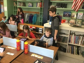7th and 8th grade students assist 4th graders with the online voting system.