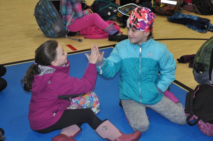Two Fletcher students greet each other with a high five during a whole-school celebration. The celebrations serve to review and practice social skills, celebrate success with behavior and build community.