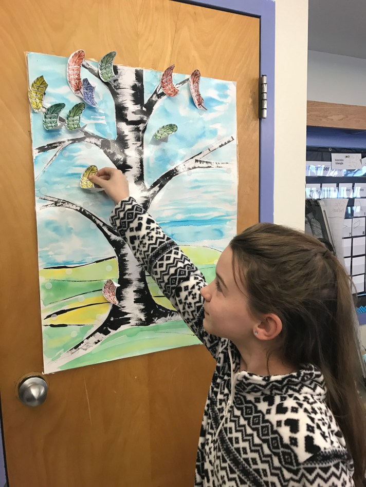 A Fletcher student puts a token on her classroom PBIS chart.
