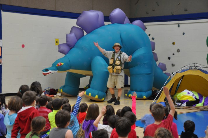 Warren, VT-based paleontologist and comedian Bob "Dinoman" Lisaius stands in front of one of three inflatable dinosaurs used during a presentation at the Fletcher Elementary School on Monday. 