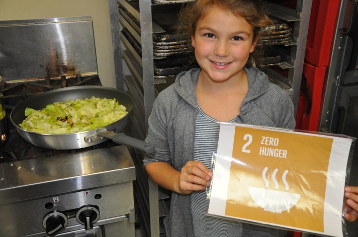 A Fletcher Elementary student poses with her harvested cabbage and UN SDG #2 Zero Hunger