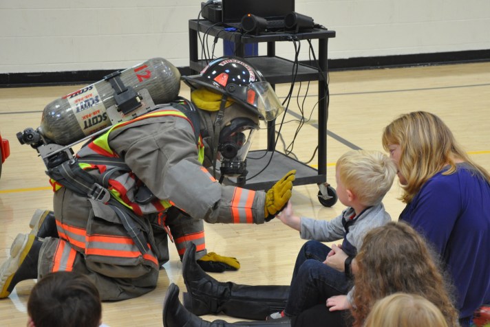 Cambridge Firefighter Elizabeth Rowe high-fives Elementary Preschooler during fire safety exercise