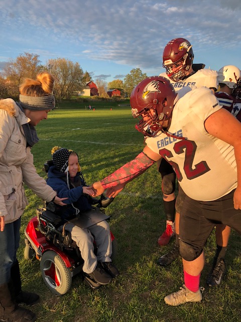 Fairfax football players greet BFA Fairfax first grader Asher Lawrence
